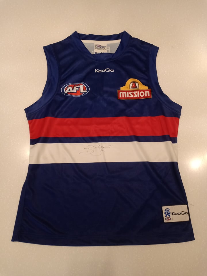 A Bulldogs jumper signed by Brad Johnson. Johnson is a 364 game legend of the club. 6 x All Australian, AFL Hall of Famer and now superstar of the media.
